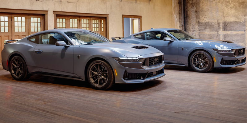 Two 2026 Ford Mustang models displayed indoors with sleek performance styling.