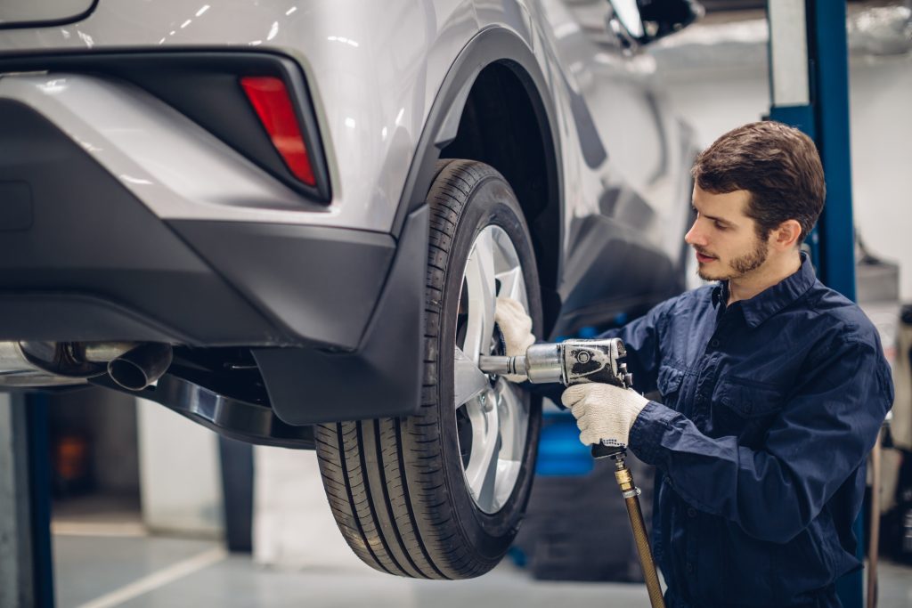 Automotive technician servicing a vehicle wheel during tire maintenance at a repair shop.